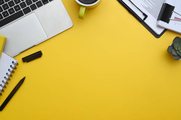 istock Laptop, notepad, coffee cup and financial reports on yellow background. Top view with copy space 2156159413