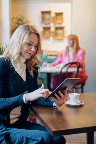 istock Blonde woman in cafe working on digital tablet 2156159692