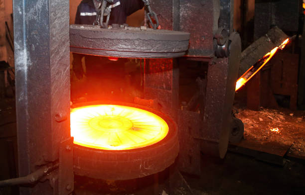 istock Press for forging glowing metal discs, sewer manholes isolated on black background. 2156160913