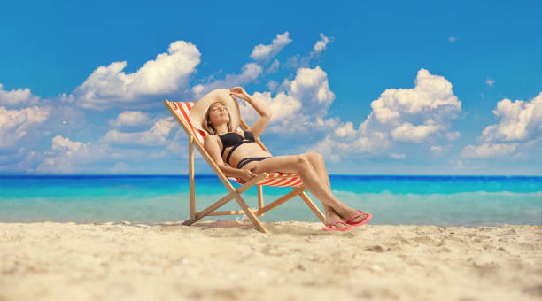 istock Attractive young female in bikini sunbathing on a beach chair 2156162097