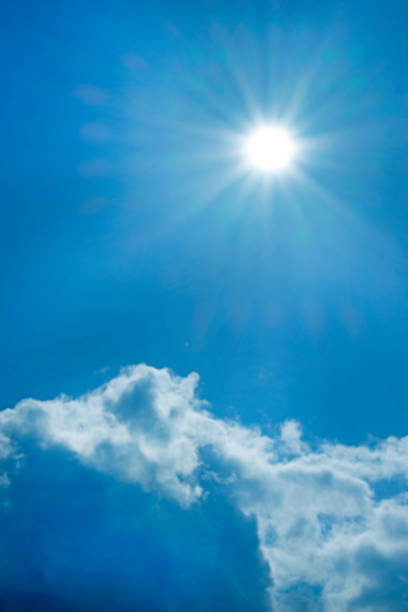 Sky. Heaven background. Cloud and bright sun with long rays on a bright blue sky.Bright sunny weather background.Beautiful natural background in blue and white colors