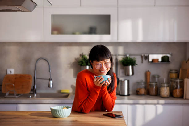 istock Woman relaxing at home drinking coffee at kitchen counter 2156167923