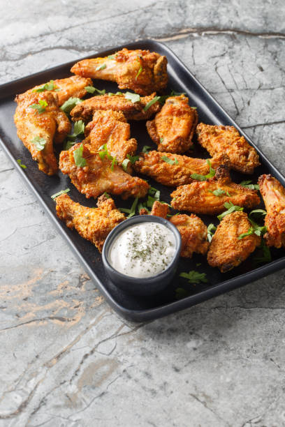 istock Crispy baked curry-breaded chicken wings close-up in a plate. Vertical 2156167993