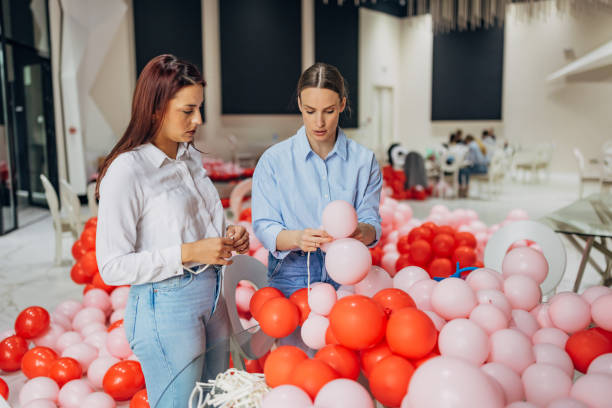 istock Two female decorators are making decorations for the celebration, blowing up balloons 2156168264