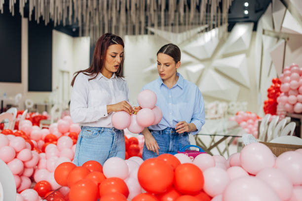 istock Two female decorators are making decorations for the celebration, blowing up balloons, tying them 2156168283