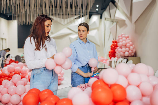 istock Two female decorators chat while making a birthday decoration with balloons in a restaurant 2156168284