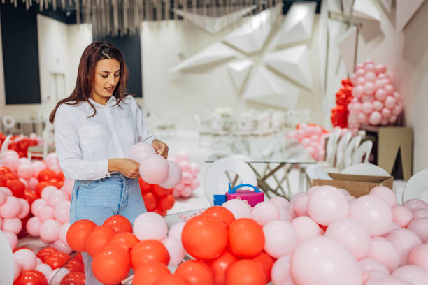 istock Female event decorator makes birthday decorations, blowing up balloons and tying them 2156168286
