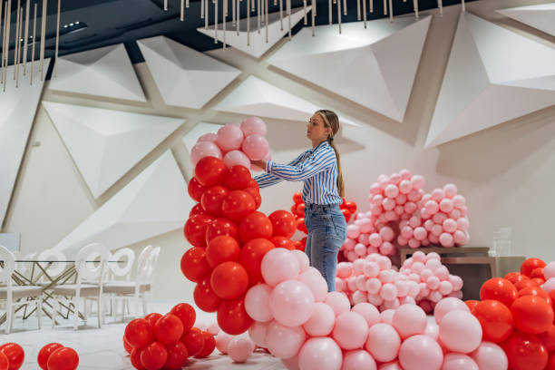 istock A decorator uses pink and red balloons while making birthday decorations in a restaurant hall 2156168304