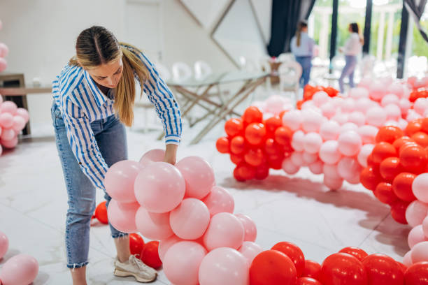 istock A female decorator ties balloons, making a huge column out of them. Making decorations for birthday parties 2156168342