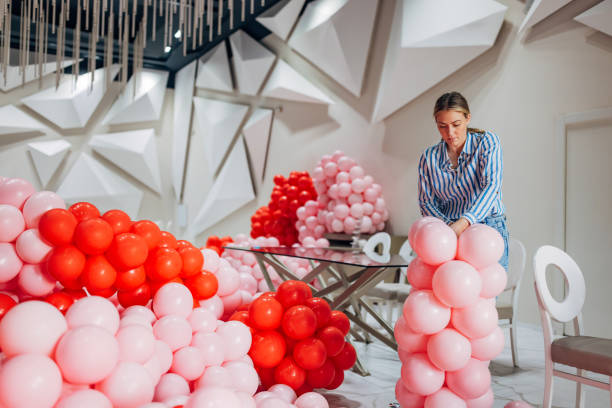 istock The decorator arranges balloon decorations, connecting them with a ribbon and making a column out of them 2156168356