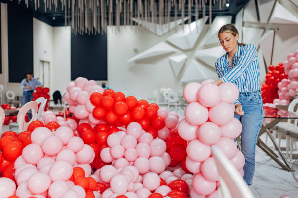 istock The decorator arranges balloon decorations, connecting them with a thin ribbon and making a column out of them 2156168389