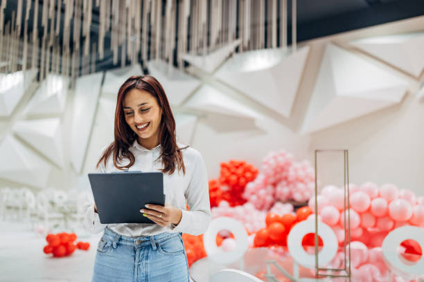 istock A smiling female party organizer crosses tasks off her to-do list while decorating a restaurant for a party 2156169030