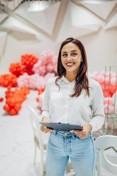 istock A cheerful female party organizer holds a clipboard in her hands while looking directly at the camera 2156169067