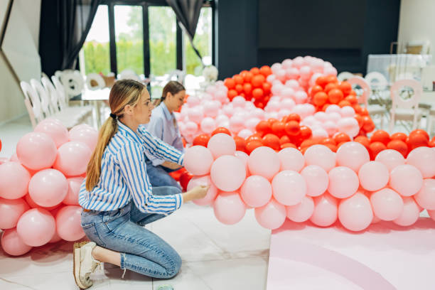 istock Two focused decorators tie balloons to make a balloon arch for a party decoration 2156169355