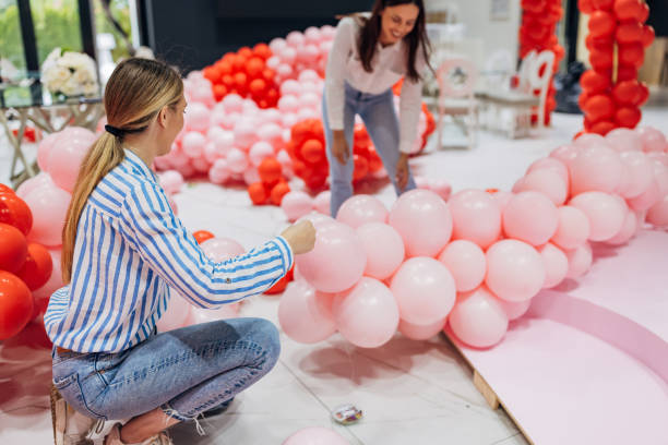istock Two smiling decorators work as a team to decorate the restaurant's hall, making a decorative balloon arch 2156169792