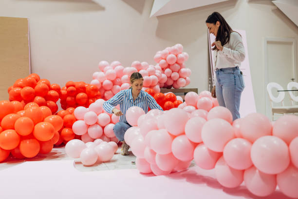 istock Two decorators work as a team to decorate the restaurant's hall, making a decorative balloon arch 2156169799