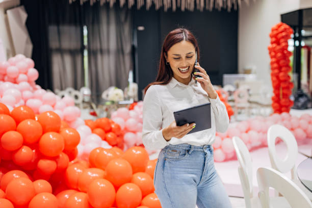 istock An event organizer talks on her mobile phone with new clients while she supervises the decoration of the party hall 2156169806