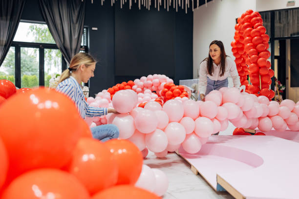 istock Two focused decorators work as a team to decorate the restaurant's hall, making a decorative balloon arch 2156169807