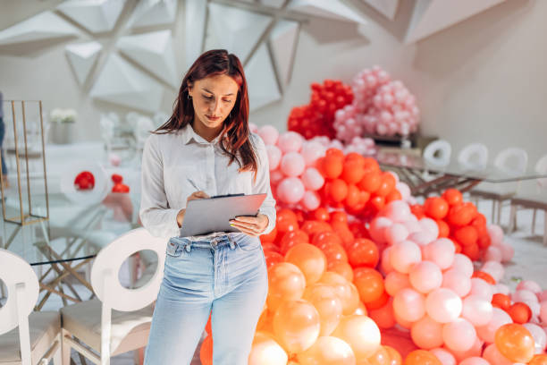 istock A female party organizer crosses tasks off her to-do list while decorating a restaurant for a party 2156170290