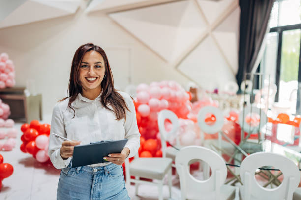 istock A smiling female party organizer holds a clipboard in her hands while looking directly at the camera 2156170292
