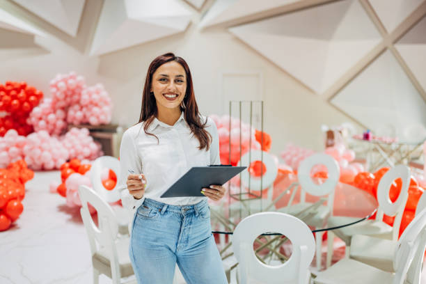 istock A cheerful female party planner holds a clipboard in her hands while looking directly at the camera 2156170315