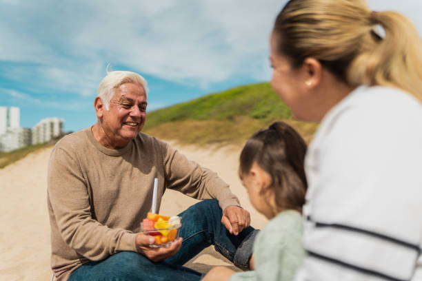 istock Family talking and eat fruit on a picnic at beach 2156170382