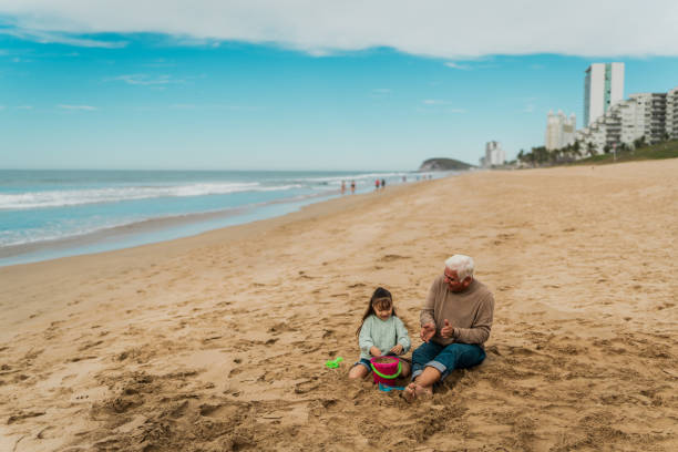 istock Grandfather playing with granddaughter on sand at beach 2156170383
