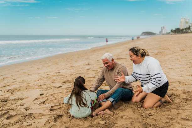 istock Family playing sand and talking at beach 2156170397