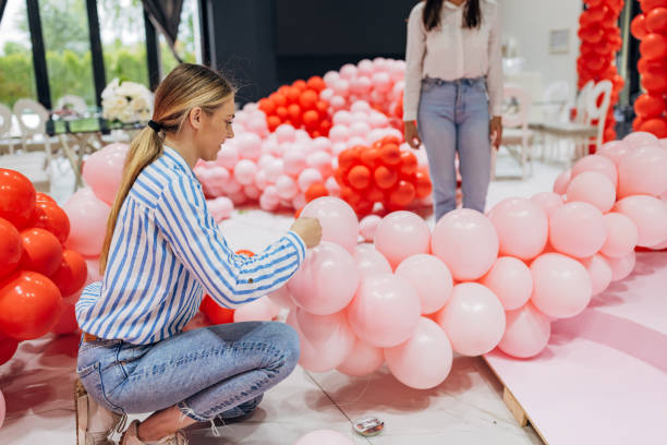 istock Two women decorators and event planners work as a team to decorate the restaurant's hall, making a decorative balloon arch 2156170401