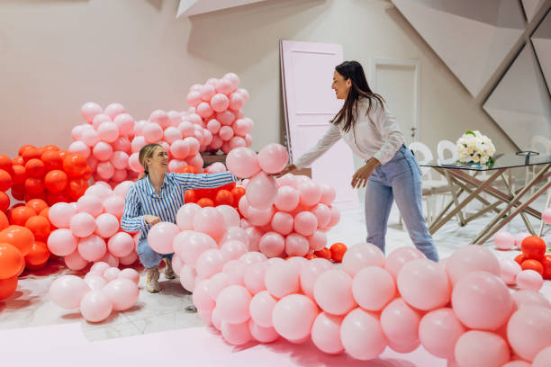 istock Two smiling decorators and event planners work as a team to decorate the restaurant's hall, making a decorative balloon arch 2156170413