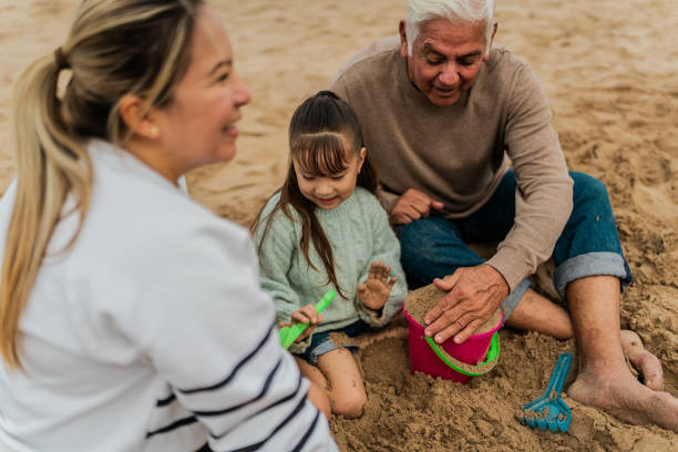 istock Family playing sand and talking at beach 2156170418