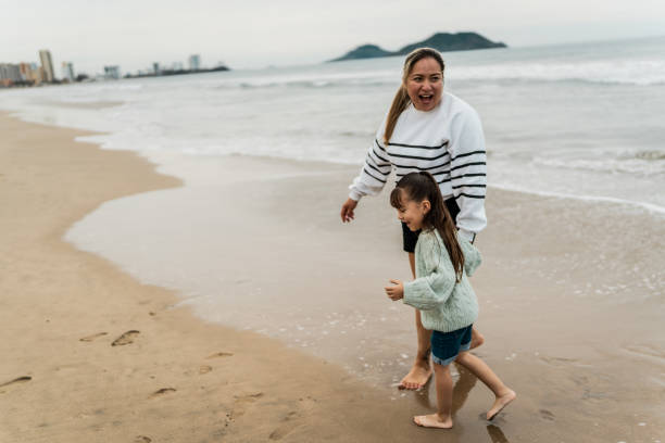 istock Mother and daughter running at beach 2156170443
