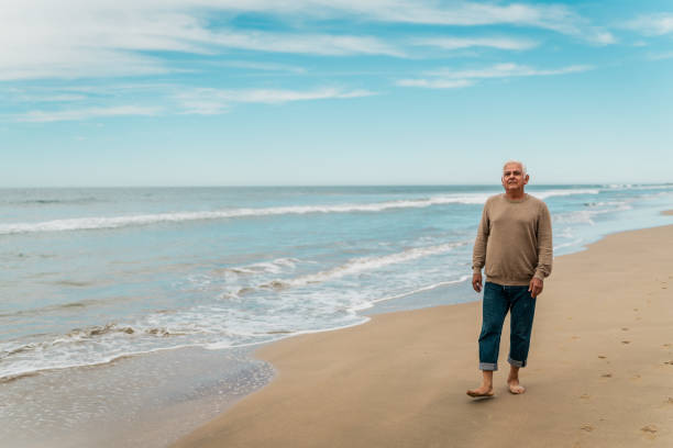 istock Senior man walking and looking around on the beach 2156170627