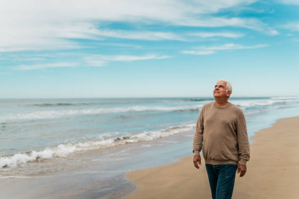istock Senior man looking around and walking on the beach 2156170628