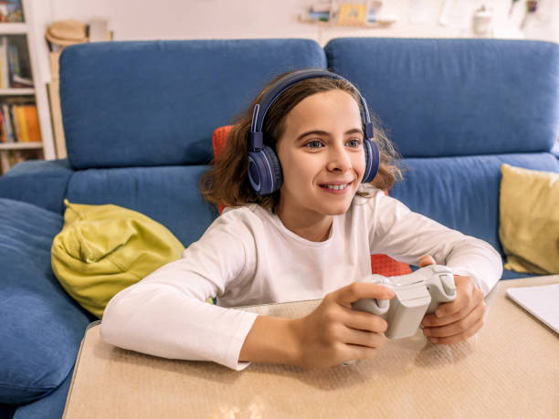 istock A smiling girl is engrossed in playing a console with a controller in her hand. 2156173611
