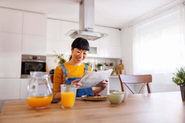 istock Woman reading newspapers and having breakfast at home 2156173717