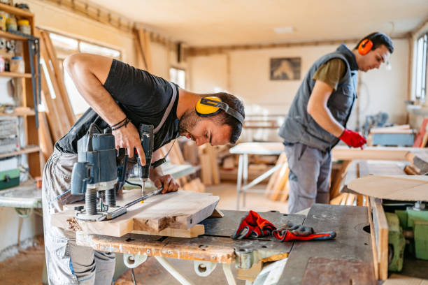 istock Young Male Carpenter Using An Electric Drill On The Wood In His Workshop 2156174769