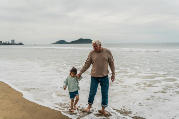 istock Grandfather talking and walking with granddaughter at beach 2156176790