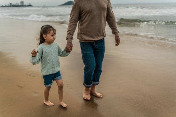 Granddaughter walking with grandfather at beach