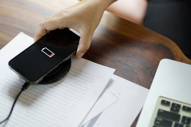 Charging mobile phone battery with wireless charging device in the table. Smartphone charging on a charging pad. Mobile phone near wireless charger Modern lifestyle technology concept