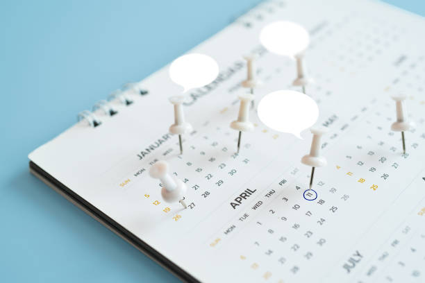 istock Close up of white thumbtack on calendar with white speech bubble on blue background 2156187331