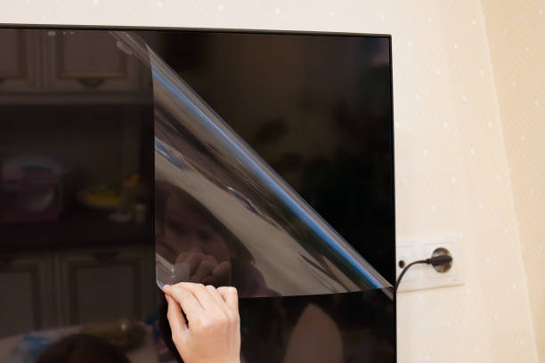 istock hand removes protective film from new tv screen 2156188451