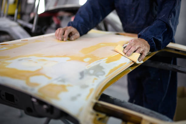istock Workman in protective suit sanding car part in garage 2156189494