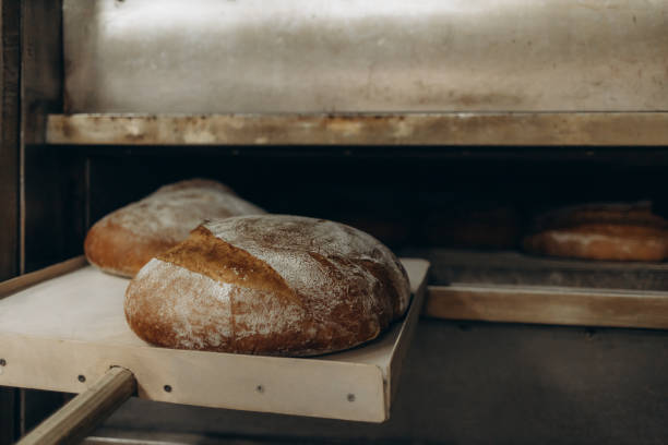 istock Baker putting bread in the bakery oven cowering on the floor of the bakery 2156201767