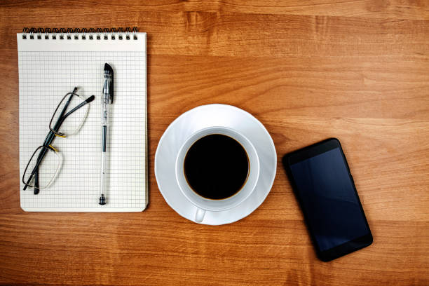 Office desk with notepad, phone and cup of coffee, office work concept