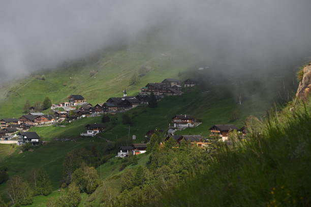 istock Picturesque mountain village surrounded by lush greenery with low clouds 2156202541