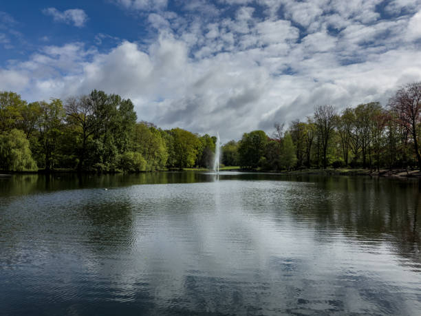 istock Park lake featuring a fountain with green trees in the background 2156202620