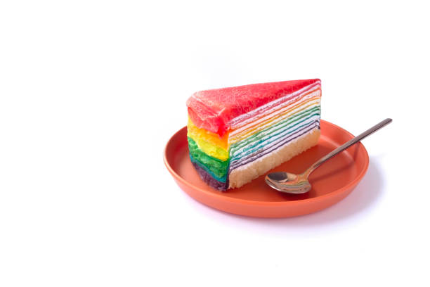 Colorful layered Slice of cream cake isolated on white background. rainbow color multilayered creamy sponge cake cut on a plate, orange background