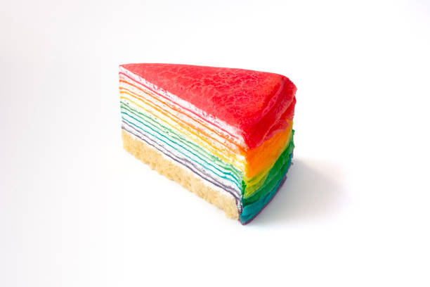 Colorful layered Slice of cream cake isolated on white background. rainbow color multilayered creamy sponge cake cut on a plate, orange background