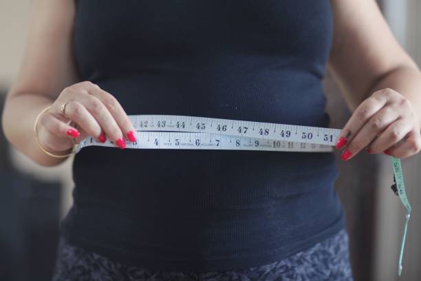 istock Women's hand holding excessive belly fat, overweight concept. 2156204012